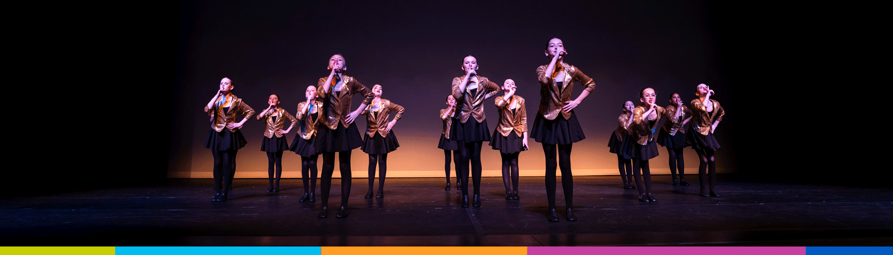 Dancers performing during a dance recital, all dancers are shushing with fingers up to their lips. 